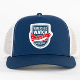 A Navy / White trucker hat with white mesh side panels and a front patch reading 'WATERSHED WATCH' with a red salmon graphic and 'Salmon Society Est. 1998'.