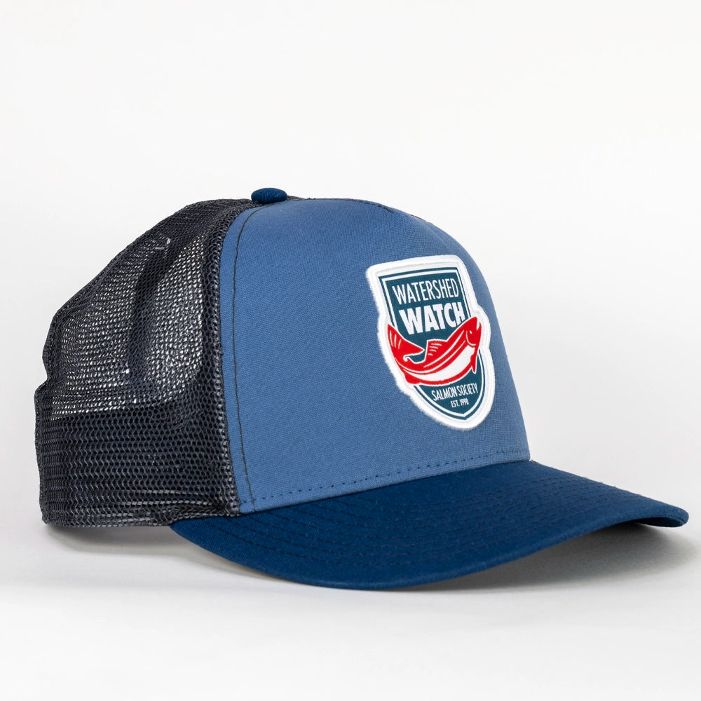 A Dusk Blue / Navy trucker hat with a black mesh back, featuring a 'Watershed Watch' logo patch on the front panel.